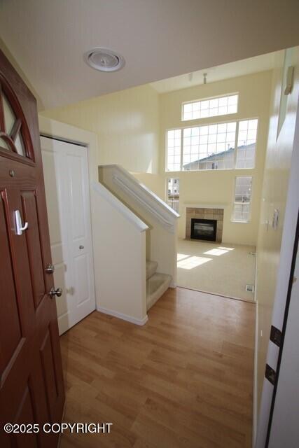 foyer entrance featuring stairs, light wood-type flooring, and a tiled fireplace