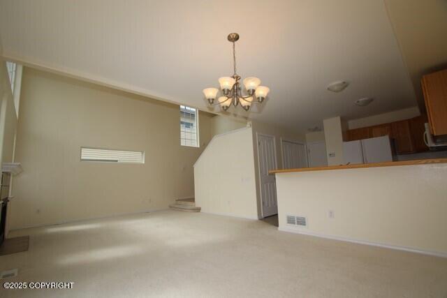 unfurnished living room with a chandelier and light colored carpet