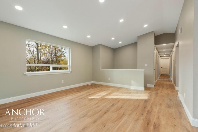 spare room with baseboards, lofted ceiling, wood finished floors, and recessed lighting