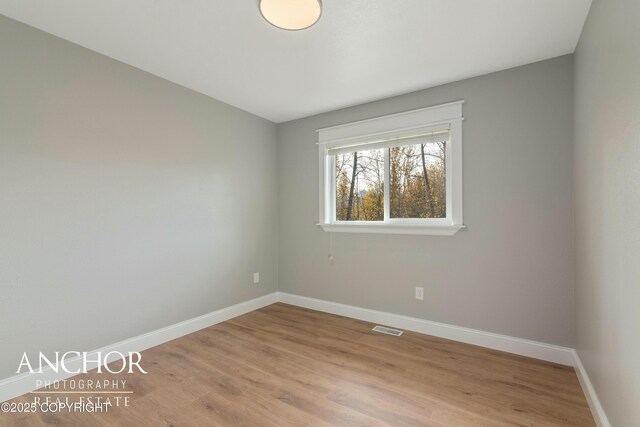 empty room with baseboards, visible vents, and light wood-style floors