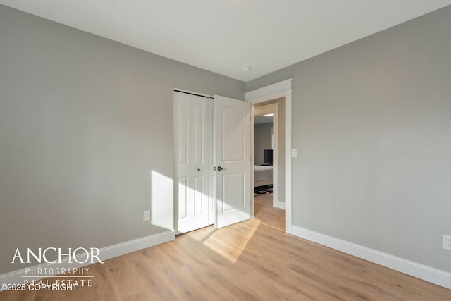 unfurnished bedroom featuring baseboards, a closet, and wood finished floors