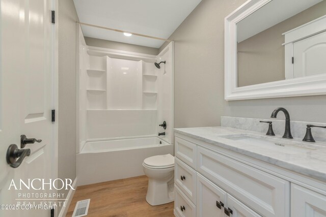 bathroom with toilet, vanity, bathing tub / shower combination, wood finished floors, and visible vents