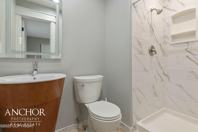 bathroom with vanity, baseboards, toilet, and a shower stall