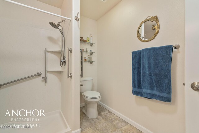bathroom with toilet, baseboards, and walk in shower