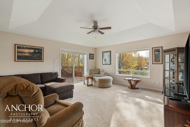living room with carpet floors, ceiling fan, and a raised ceiling