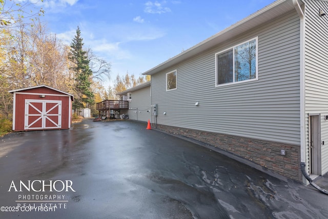 view of home's exterior featuring stone siding, an outdoor structure, and a storage shed