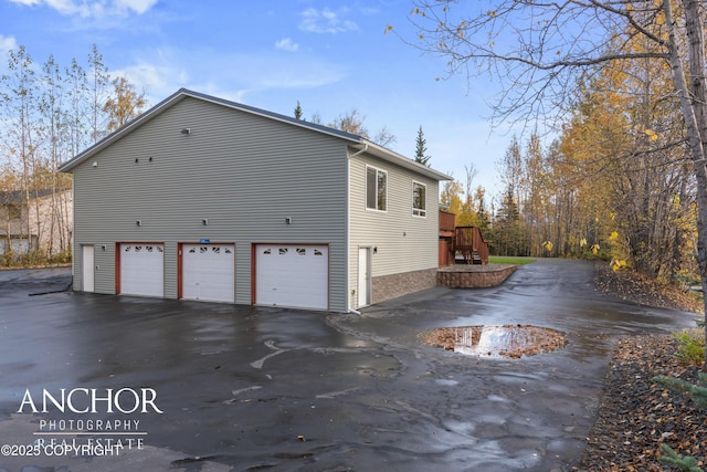 view of side of home with an attached garage and aphalt driveway