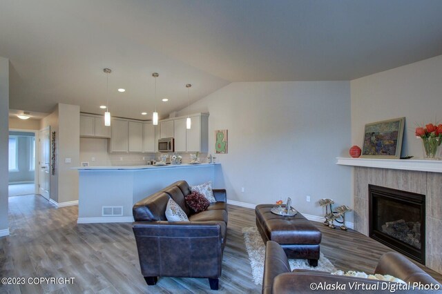 300 Shageluk St, Anchorage, AK 99504 - living room featuring vaulted ceiling, baseboards, visible vents, a fireplace, and wood finished floors