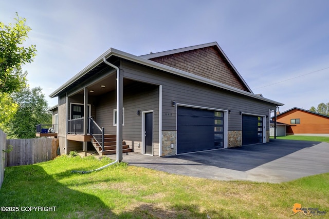 648 E 73rd Ave # 2, Anchorage, AK 99518 - view of property exterior with driveway, a garage, and stone siding