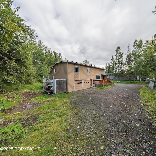 7621 E 4th Ave, Anchorage, AK 99504 - back of property with driveway, a deck, and an attached garage