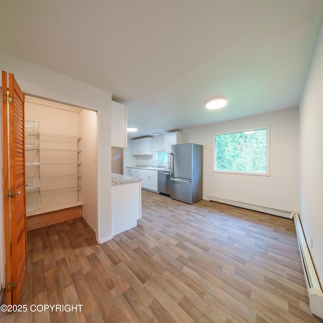 7621 E 4th Ave, Anchorage, AK 99504 - kitchen featuring light wood-type flooring, white cabinets, appliances with stainless steel finishes, and baseboard heating