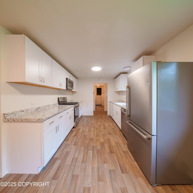7621 E 4th Ave, Anchorage, AK 99504 - kitchen featuring white cabinetry, appliances with stainless steel finishes, light stone counters, and light wood finished floors