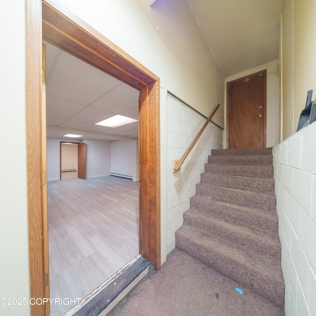 7621 E 4th Ave, Anchorage, AK 99504 - stairway with concrete block wall, wood finished floors, baseboard heating, and a paneled ceiling