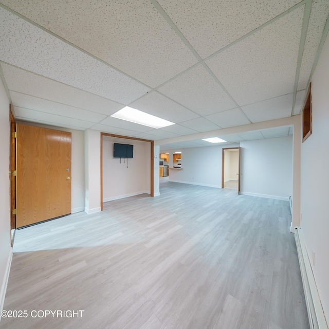 7621 E 4th Ave, Anchorage, AK 99504 - finished basement featuring baseboards, wood finished floors, a baseboard heating unit, and a paneled ceiling