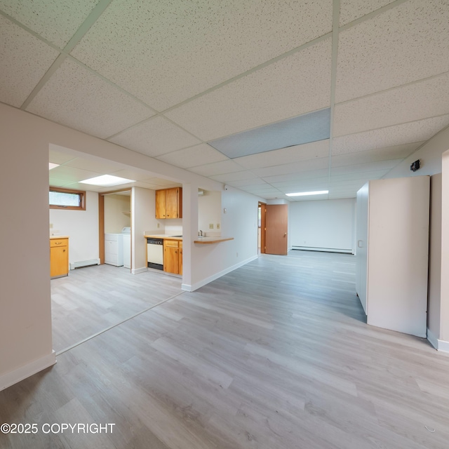 7621 E 4th Ave, Anchorage, AK 99504 - unfurnished living room with a drop ceiling, light wood-style flooring, baseboards, and a baseboard heating unit