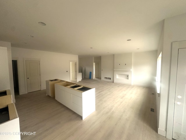 kitchen with open floor plan, white cabinets, light wood-type flooring, and visible vents