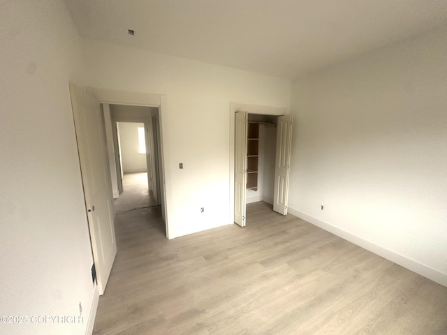 unfurnished bedroom featuring a closet, light wood finished floors, and baseboards