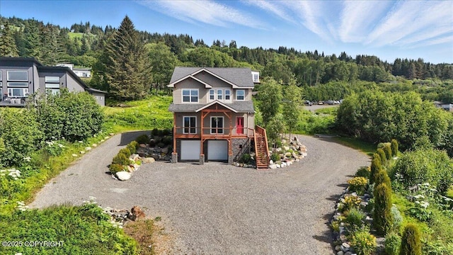 3866 Cabana Ct, Homer, AK 99603 - view of front of house featuring a view of trees, gravel driveway, stairs, stone siding, and a garage