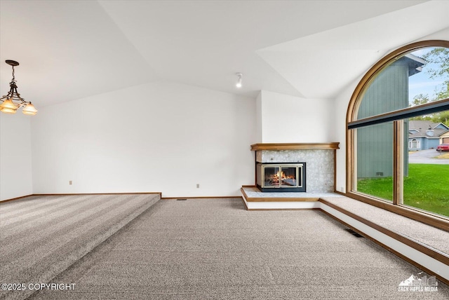 unfurnished living room featuring carpet, lofted ceiling, a glass covered fireplace, and baseboards