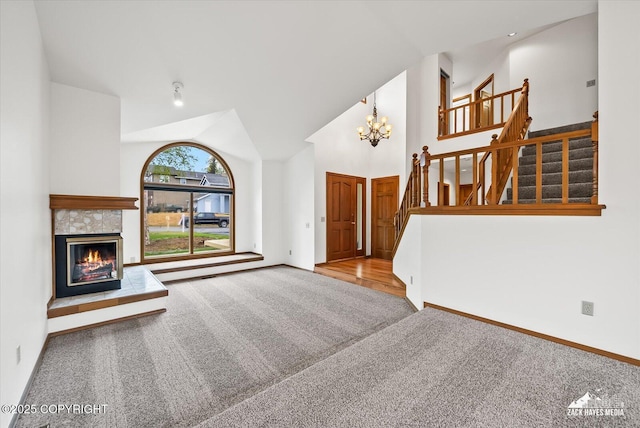 foyer featuring carpet flooring, a chandelier, stairway, baseboards, and a fireplace