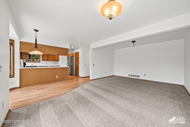 unfurnished living room with light carpet and baseboards