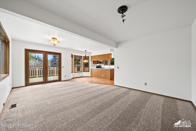 unfurnished living room with light carpet and baseboards