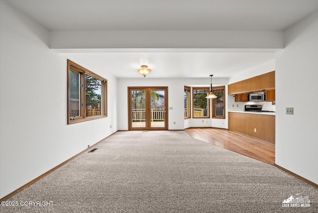 unfurnished living room with light colored carpet and baseboards