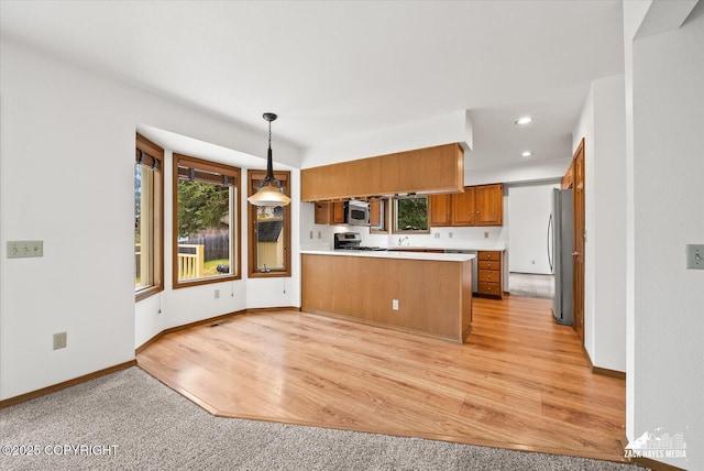 kitchen with stainless steel appliances, brown cabinetry, a peninsula, baseboards, and light countertops
