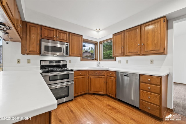 kitchen with appliances with stainless steel finishes, brown cabinetry, and light wood finished floors