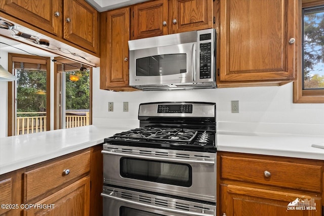 kitchen with stainless steel appliances, brown cabinetry, and light countertops