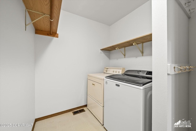 clothes washing area featuring independent washer and dryer, light flooring, and baseboards