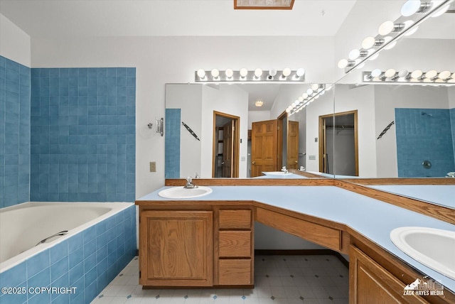 full bath featuring a relaxing tiled tub, vanity, and tile patterned floors