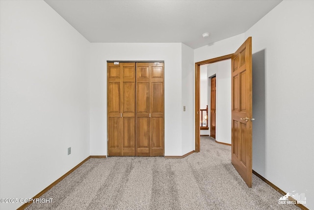 unfurnished bedroom featuring light colored carpet, baseboards, and a closet