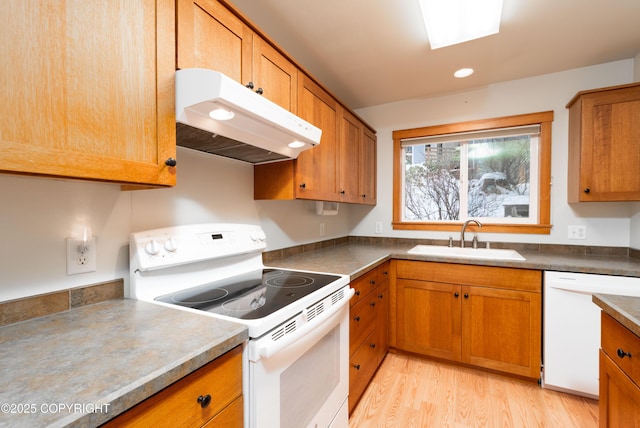 5751 N Tongass Hwy, Ketchikan, AK 99901 - kitchen with a sink, brown cabinetry, light wood-style flooring, under cabinet range hood, and white appliances