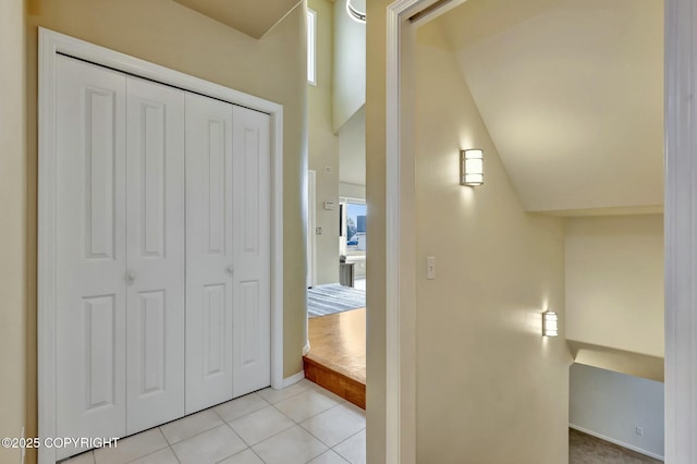 hall with baseboards, vaulted ceiling, and light tile patterned floors