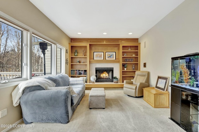 living area featuring baseboards, a warm lit fireplace, carpet floors, and recessed lighting