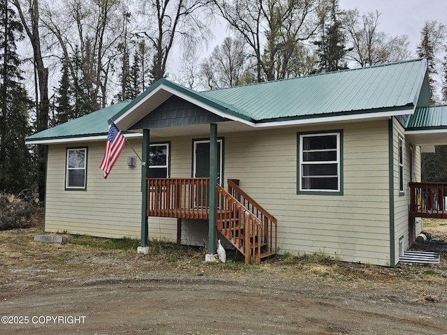 view of front facade featuring covered porch, metal roof, and stairway