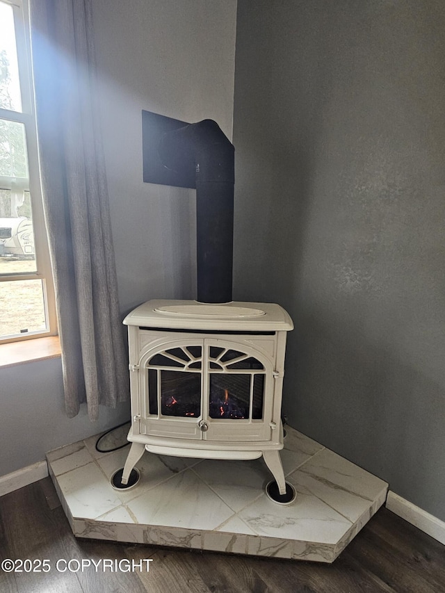 detailed view of baseboards, wood finished floors, and a wood stove