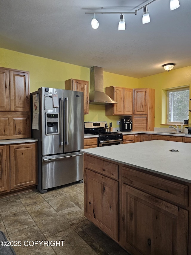 kitchen featuring stainless steel appliances, wall chimney range hood, a sink, and light countertops