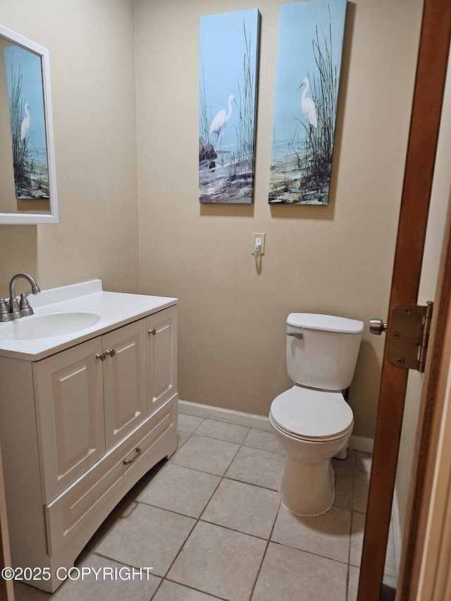 bathroom featuring toilet, vanity, baseboards, and tile patterned flooring