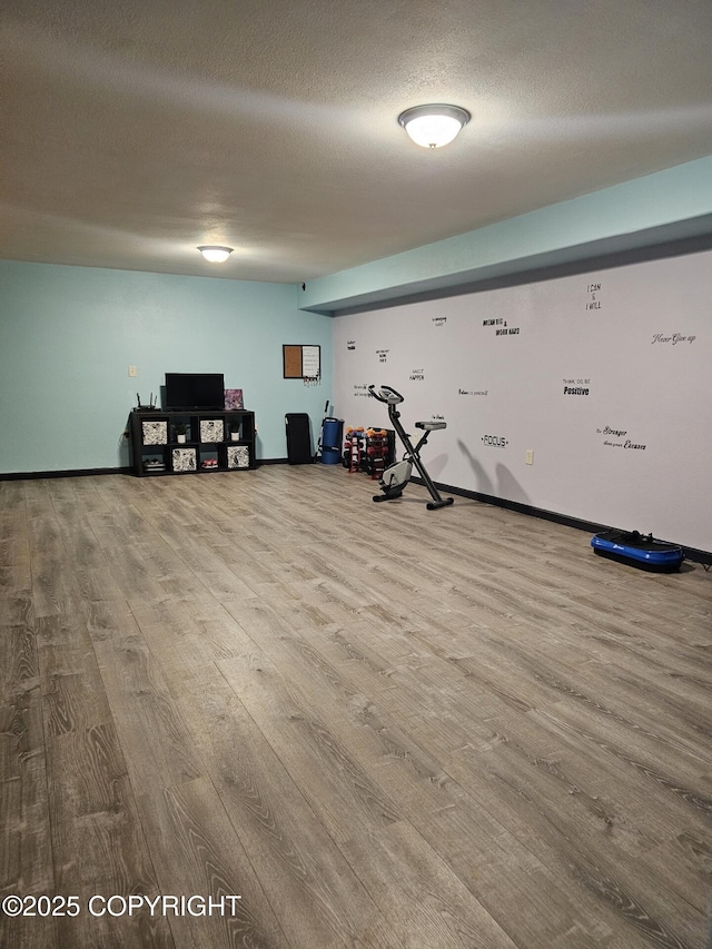 workout room featuring wood finished floors, a textured ceiling, and baseboards