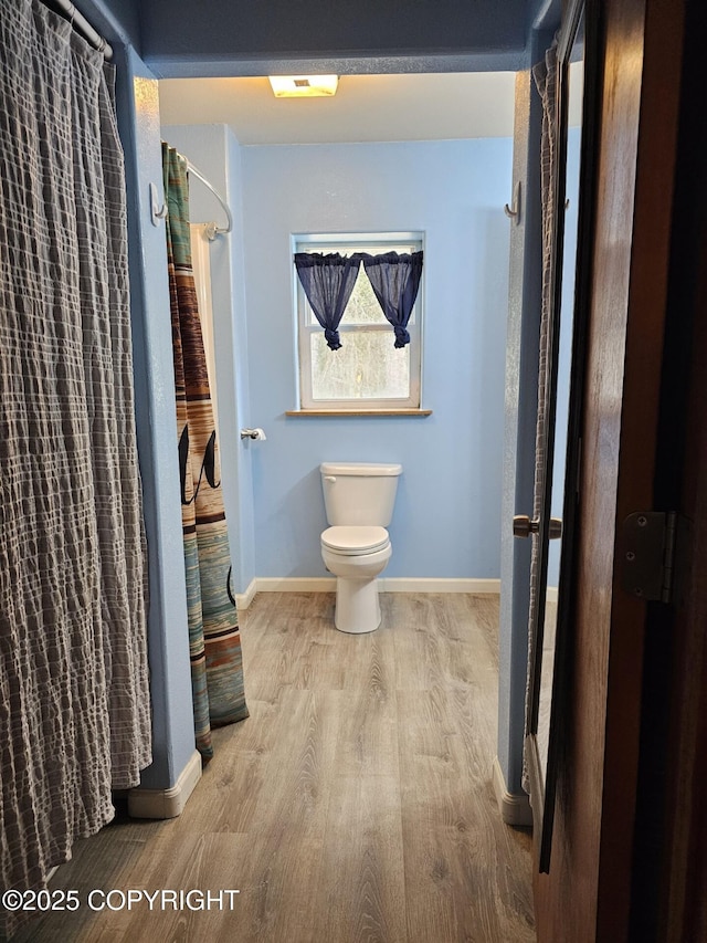 full bathroom with wood finished floors, toilet, baseboards, and a shower with shower curtain