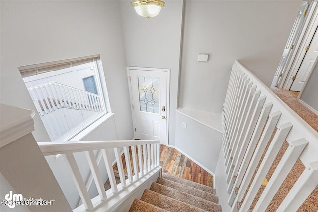 staircase featuring wood finished floors and a towering ceiling