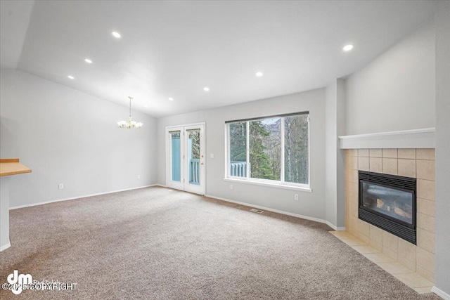 unfurnished living room featuring vaulted ceiling, a tile fireplace, a notable chandelier, carpet flooring, and recessed lighting
