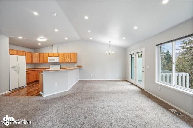 kitchen with visible vents, a peninsula, a chandelier, carpet flooring, and white appliances