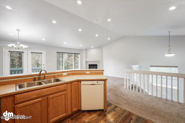 kitchen with a sink, a fireplace, dishwasher, vaulted ceiling, and pendant lighting