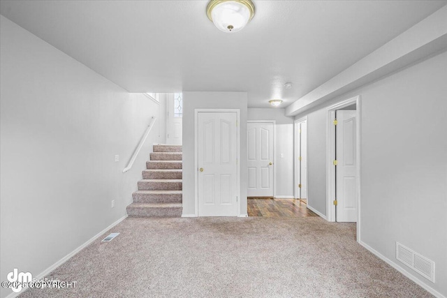 basement with visible vents, stairs, carpet, and baseboards