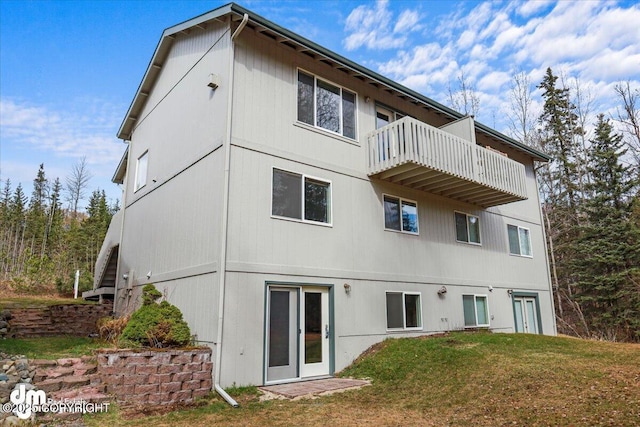 rear view of house with a lawn and a balcony