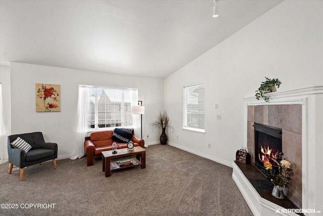 carpeted living room with a fireplace, baseboards, and lofted ceiling