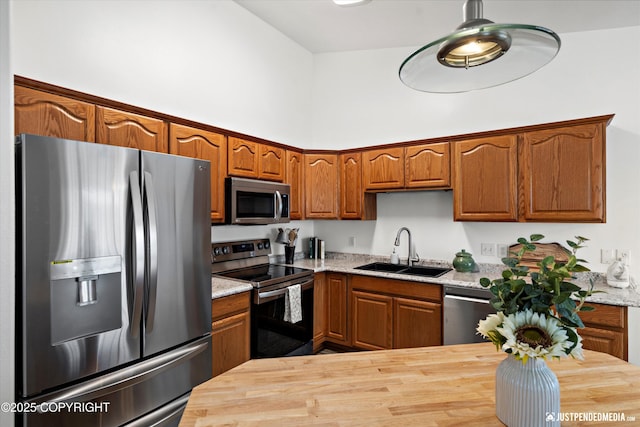 kitchen featuring butcher block countertops, brown cabinets, a sink, and stainless steel appliances